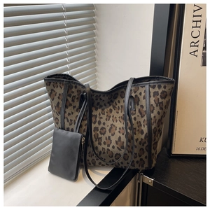 Detail of leopard print tote bag with black leather handles and matching inner pouch