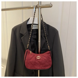 Close-up of quilted burgundy suede shoulder bag with golden chain and metal buckle