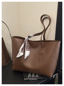 Detail of dark brown tote bag with leather texture and decorative heart scarf