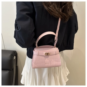 Detail of light pink crocodile pattern handbag with golden turn-lock and slim strap