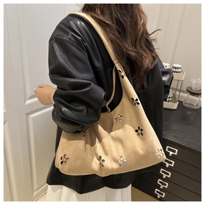 Detail of hobo bag with floral laser-cut patterns and integrated shoulder strap
