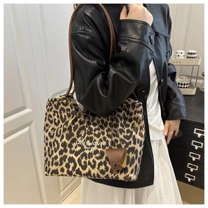 Detail of leopard print tote bag with brown straps and logo on canvas material