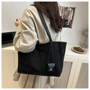 Detail of black suede tote bag featuring a matching mini charm pouch and slim shoulder straps