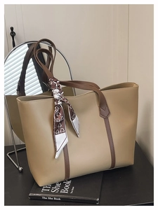Detail of beige tote bag with brown straps and a decorative patterned silk scarf