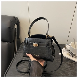 Detail of black crocodile texture bag with gold twist lock and fine handle