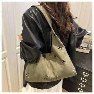 Detail of army green canvas tote bag with laser-cut flower patterns worn by model