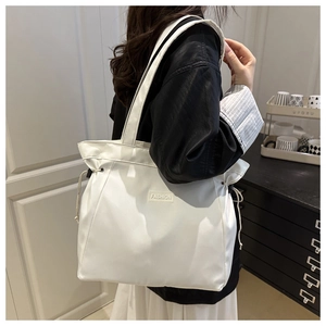 Detailed side view of a white nylon tote bag with drawstring side and fashion label