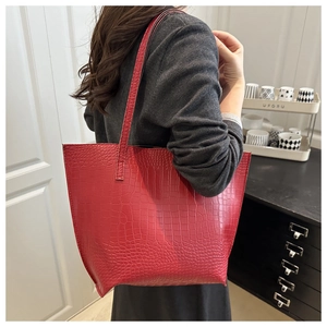 Detail of red crocodile texture tote bag showing large capacity and shiny finish on model