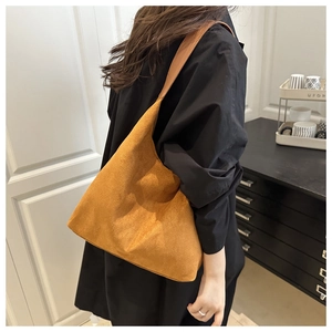 Detail view of brown suede tote bag featuring a spacious design and wide shoulder strap