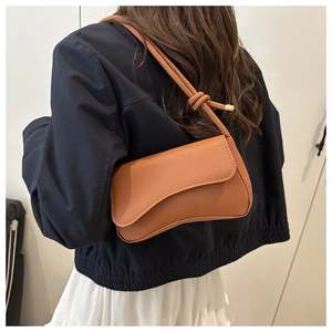 Brown leather baguette bag with knotted shoulder strap detail shown on model back