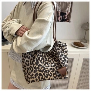 Détail d'un grand sac cabas à motif léopard avec bandoulières brunes et accessoire en cuir