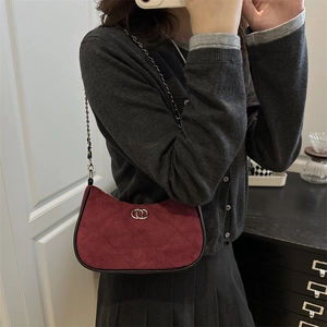Chic burgundy quilted suede shoulder bag with gold hardware and chain strap on model