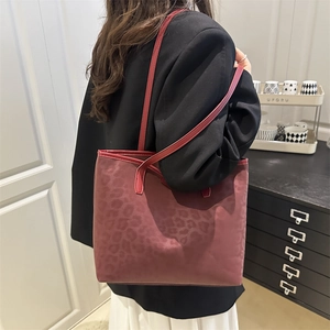 Chic dark red leopard print tote bag with shoulder strap shown on model in a modern home