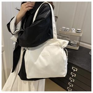 Detail of white nylon tote bag with drawstring side and FASHION label on shoulder