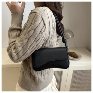 Close-up of black Saffiano leather crossbody bag with curved flap and thin shoulder strap