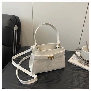 Detail of white crocodile embossed texture on a chic small square handbag with gold buckle