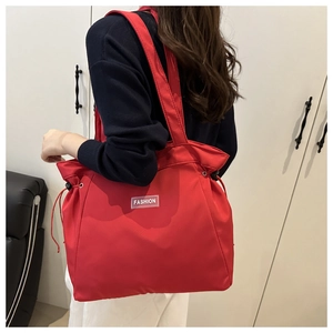 Detail of red large capacity tote bag with drawstring closure and fashion label