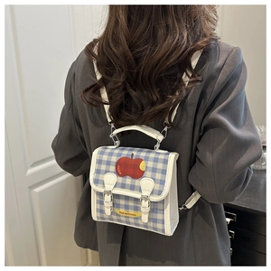 Close-up of blue plaid backpack with apple print and white leather strap details