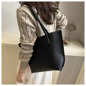 Detail of black crocodile pattern tote bag with double shoulder straps on model