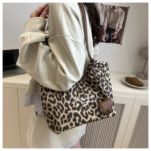 Détail du sac cabas léopard avec anses en cuir marron et un mini accessoire de charme