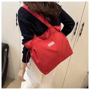 Detail showing the red nylon tote bag with drawstring closure and fashion label