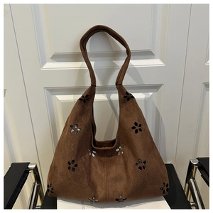 Détail de motifs floraux découpés au laser sur un sac cabas en daim marron vintage