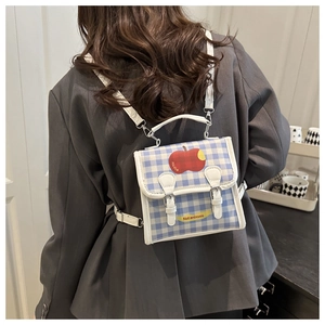 Model wearing a small blue and white checkered backpack with apple patch detail