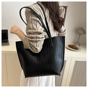 Close-up of black crocodile pattern tote bag with shoulder straps on office background