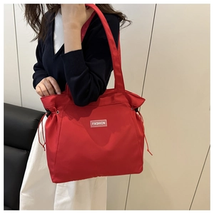 Detail of red tote bag with white fashion tag and drawstring on modern sofa