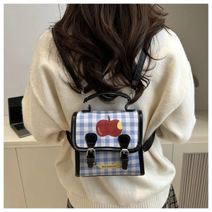 Close-up of blue and white plaid backpack featuring red apple patterns on a model's back