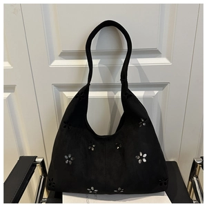 Détail du sac cabas en daim noir avec découpes florales et accents métalliques argentés