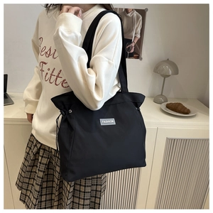 Close-up of black canvas tote bag with FASHION label and drawstring detail for daily use