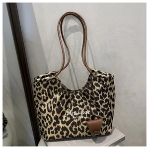 Detailed view of leopard print tote bag with brown leather handles and small pouch