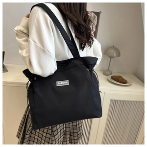 Side view of black nylon tote bag with drawstring detail and Fashion label on model