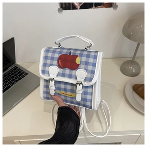 Detail of blue plaid mini backpack featuring a red apple graphic on a white desk