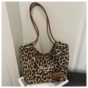 Close-up of leopard print canvas tote bag with brown cord handles and leather charm