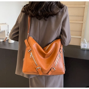 Detail of orange faux leather tote bag with silver zippers and adjustable shoulder strap