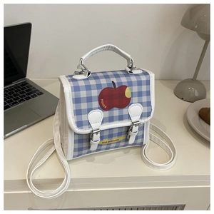 Detail of blue and white checkered backpack with red apple print and yellow label