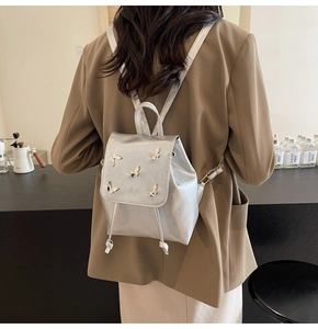 Silver leather backpack featuring 3D metal butterfly charms and drawstring closure