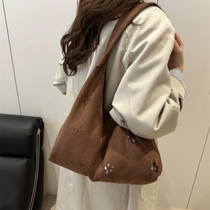 Sac hobo vintage en daim marron avec motifs floraux découpés au laser porté à l'épaule