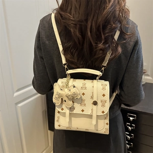 Mini cream backpack with brown bear prints and matching teddy charm on model back