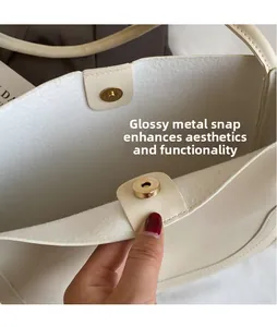 Detail of the golden magnetic hardware clasp on a creamy white leather bucket bag