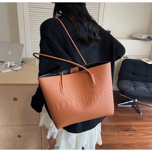 Vue détaillée du sac cabas en cuir marron avec logo embossé dans un bureau moderne