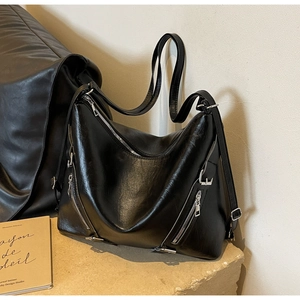 Detail of a large black tote bag in glossy leather with silver zippers and soft texture