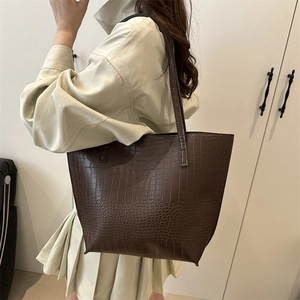 Chic dark coffee tote bag with crocodile texture worn by a model in a minimalist setting