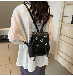 Detailed view of black matte leather mini backpack featuring silver butterfly accents on the flap