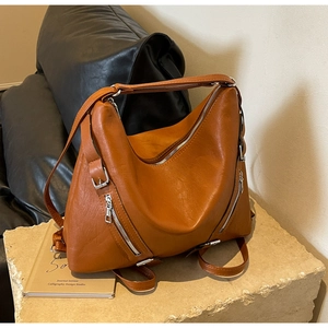 Close-up of vintage brown tote bag texture and functional silver zippers on stone surface