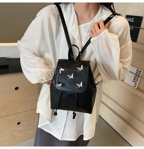 Detail of black PU backpack featuring silver butterfly studs and a drawstring flap closure