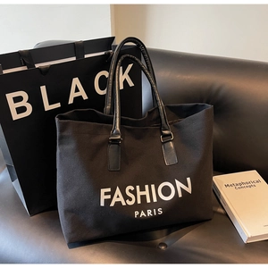 Detalle del bolso tote de lona negra con letras blancas FASHION PARIS y asas de cuero