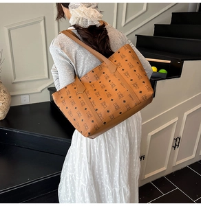 Classic brown tote bag featuring textured faux leather and bear monogram pattern shown on model